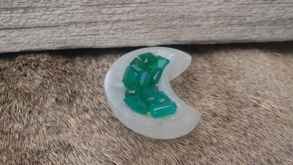 Small crescent selenite bowl on background of wood and fur. Gems inside as example of possible contents.